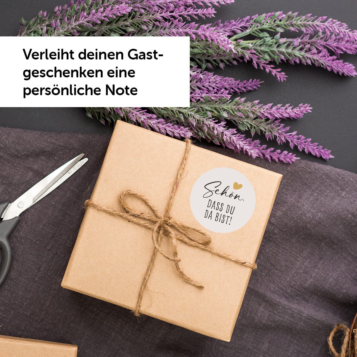 Geschenkverpackung mit Aufkleber "Schön, dass du da bist" für persönliche Gastgeschenke, Umgeben von Lavendel und Schere.