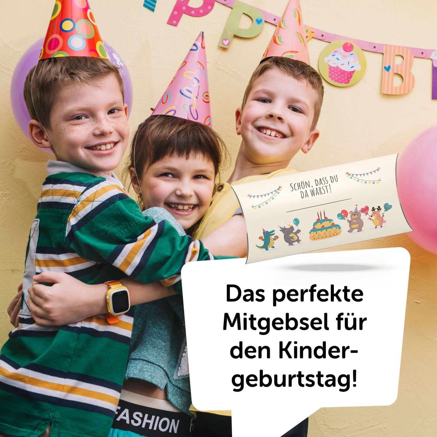 Drei Kinder mit Partyhüten umarmen sich, halten ein Mitgebsel für den Kindergeburtstag in der Hand.