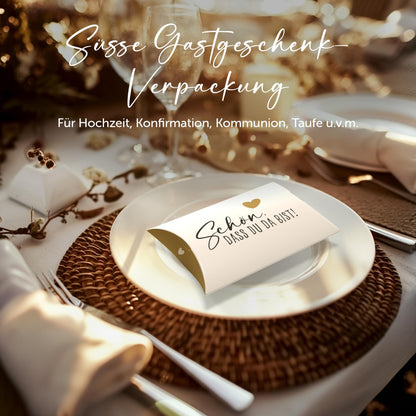 Schachtel mit Aufschrift "Schön, dass du da bist" auf einem gedeckten Tisch, ideal für Hochzeiten und Feiern.